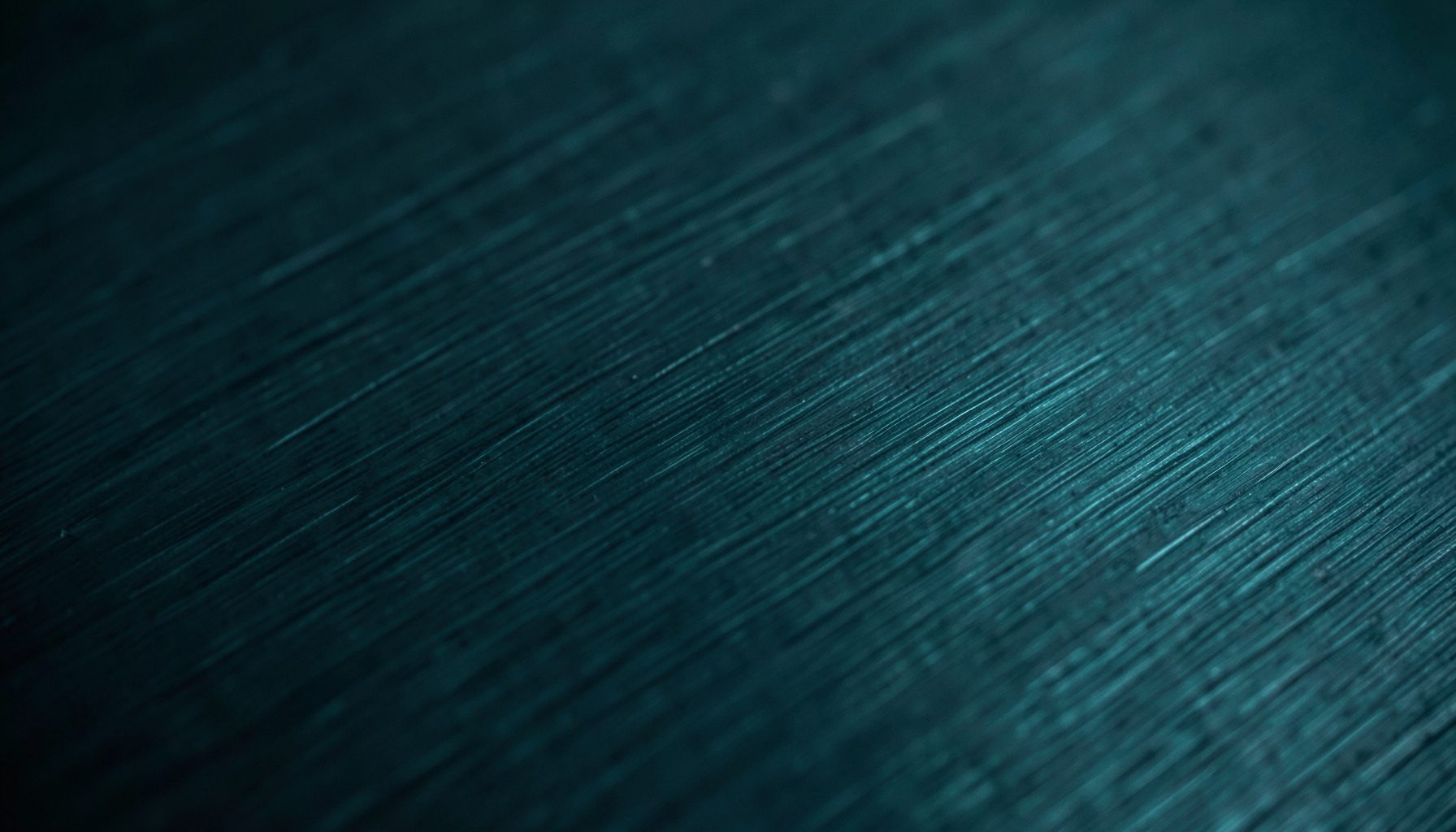 Extreme close-up of a dark brushed-metal surface with faint diagonal grain lines, deep charcoal and slate tones, moody and industrial.